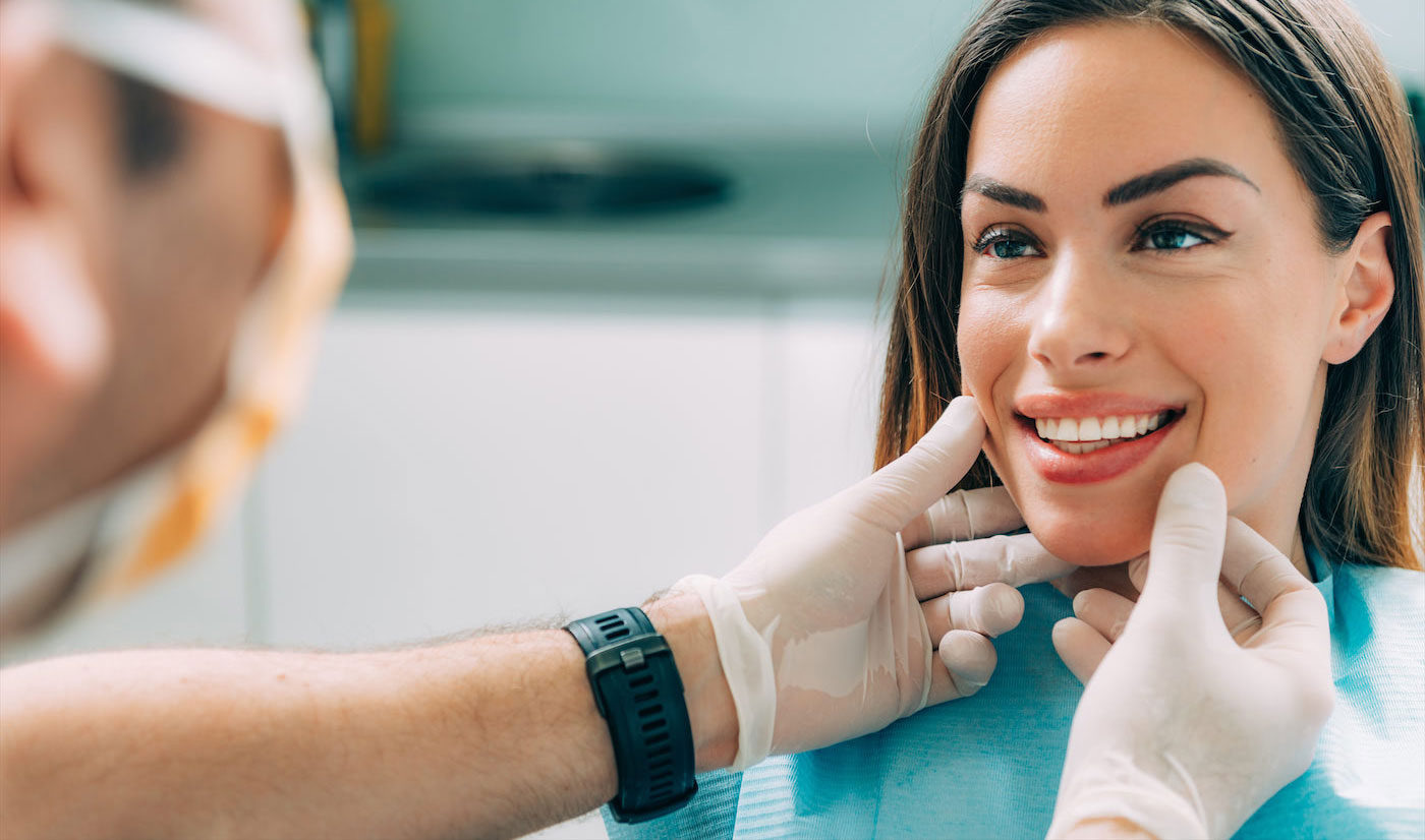 A woman receiving dental care, with a smiling expression, while seated in a dental chair.