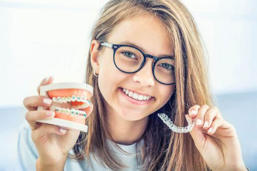 Smiling young woman holding a toothbrush with toothpaste, showcasing dental hygiene.