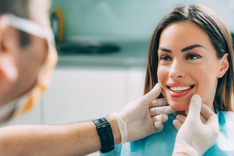 A woman receiving dental care from a professional, with both smiling.