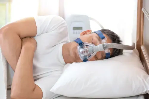 A person sleeping in bed with a CPAP machine.