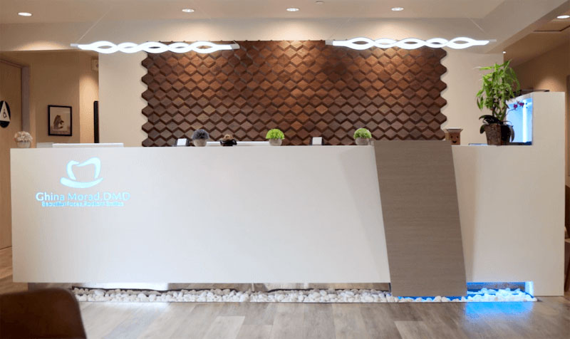 The image shows an interior space, likely a reception area or lobby, featuring a white counter with a logo that reads CASA DEL SOL and a large decorative wall behind it. The wall has a textured design and is adorned with vertical elements resembling a wavy pattern.